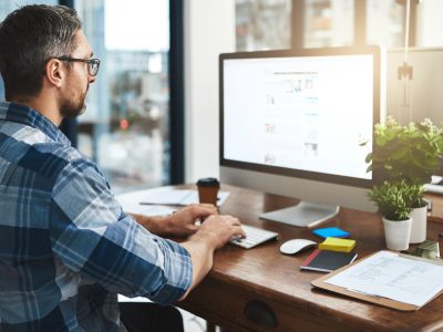 man sitting at a desk on typing on an imac keyboard in an office - tungsten network total ap