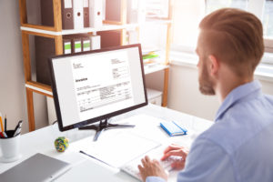 Businessperson Calculating E-Invoice Online On Computer At Office