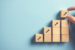 Hand arranging wood block stacking as step stair on paper pink background. Business concept growth success process, copy space