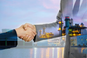 businessmen handshake on the factory background