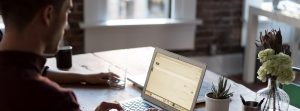 man sitting at a wooden table with laptop open - Tungsten Network