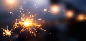 Glittering burning sparkler against blurred bokeh light background